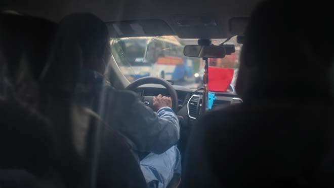 سائق تاكسي ، يرتدي بدلة واقية وغطاء بلاستيكي يفصل نفسه عن الركاب